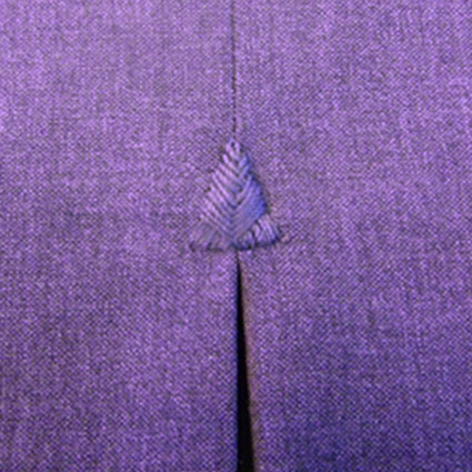 Eine handgestickte Fliege in Form eines Dreieckes ist am Anfang einer Falte abgebildet.